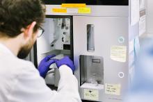 A researcher with gloved hands uses a cell sorter in a UCSF laboratory.