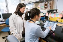 Jennifer Rosenbluth, MD, PhD, and Tam Binh Bui, MSc, MD, look at data on a laptop while working together in the Rosenbluth Lab at UCSF’s Parnassus Heights Campus.