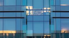 The Byers Hall facade with offices and a bicycle, reflects sunset light on Mission Hall, at the Mission Bay campus.