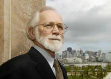 UCSF Chancellor Emeritus Michael Bishop stands outdoors with downtown San Francisco in the background.