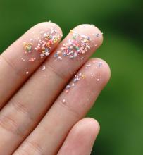 Microplastic particles on the tips of the fingers of a hand