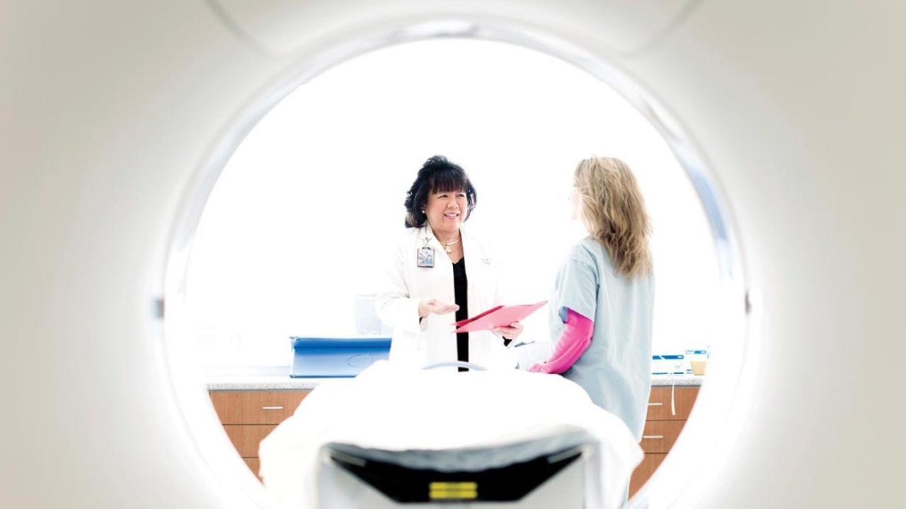 Judy Yee leads a patient to an MRI machine