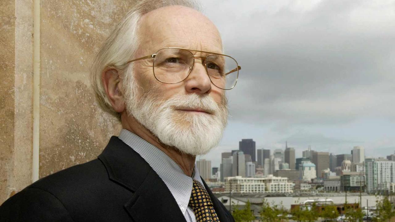 UCSF Chancellor Emeritus Michael Bishop stands outdoors with downtown San Francisco in the background.