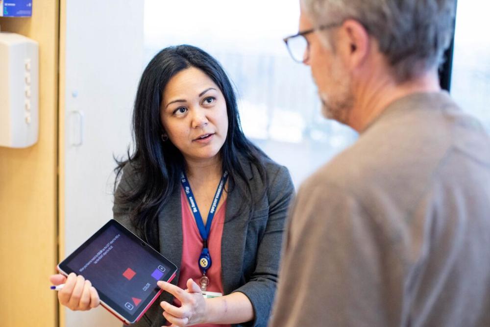 A male patient listens to a female nurse, who is talking while pointing to an iPad, in a clinic at the UCSF Medical Center at Parnassus Heights.