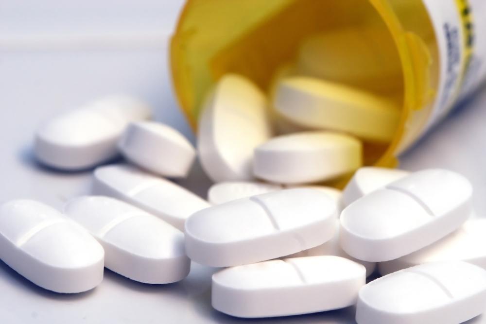 white oblong pills spilling out of a bottle