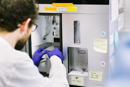 Scientist in white lab coat using a cell sorter 