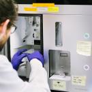 A researcher with gloved hands uses a cell sorter in a UCSF laboratory.