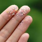 Microplastic particles on the tips of the fingers of a hand