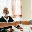 Three senior citizens shaking hands across a table
