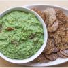 green dip in bowl next to plate of whole grain crackers